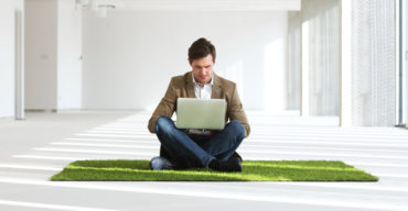 Homem sentado em cima do tapete tipo grama: saiba como escolher tapete