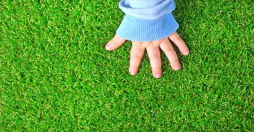 Vemos uma mão de criança. Saiba porque usar grama sintética em sala de aula infantil!