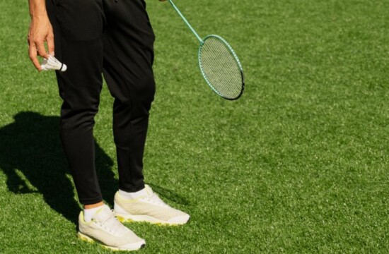 Grama sintética no badminton: conheça esse estilo de gramado e seus benefícios Atleta testando a grama sintética no badminton, com seus equipamentos em mão.