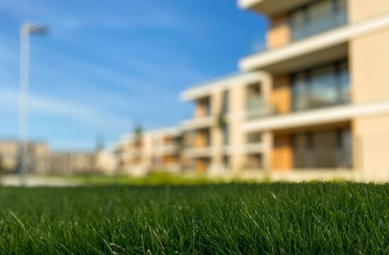 Aprenda a fazer limpeza de grama sintética com a Stampa Gramas! Gramado artificial em primeiro plano em um condomínio, ilustrando a limpeza grama sintética.