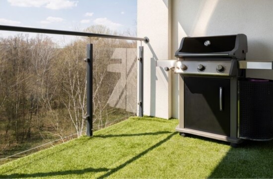 Conheça 3 usos do tapete verde com a Stampa Gramas! Varanda com churrasqueira e chão coberto por tapete verde artificial.