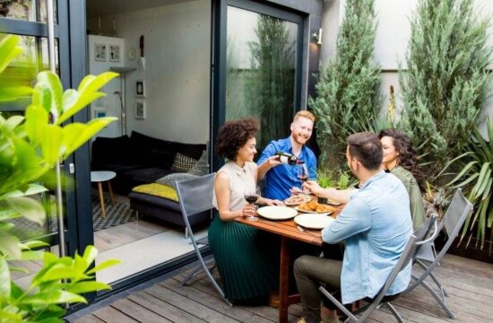 Conheça os jardins contemporâneos com a Stampa Gramas! Amigos confraternizam em área externa decorada com plantas de jardins contemporâneos.